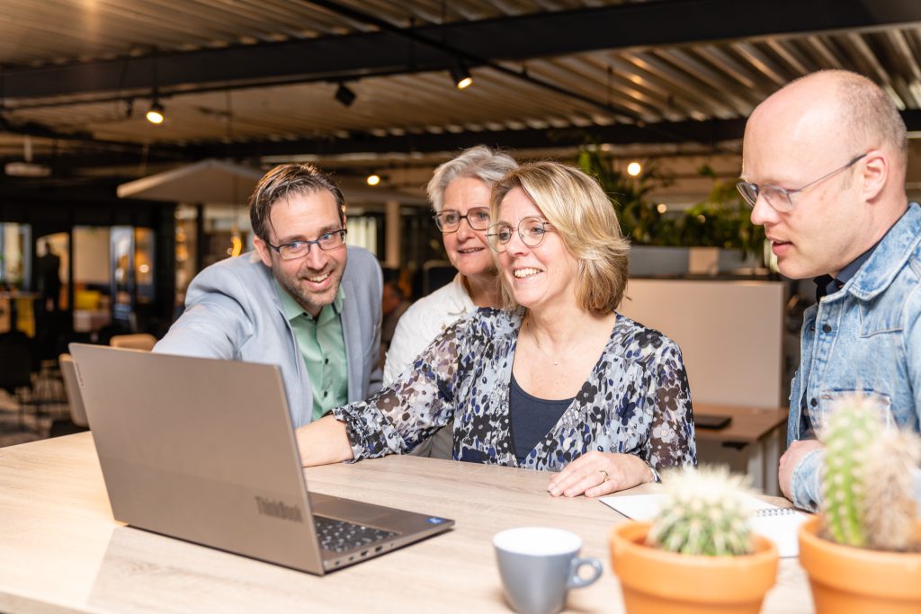 Een groep professionals werkt samen achter een laptop aan digitale transformatie en strategie.