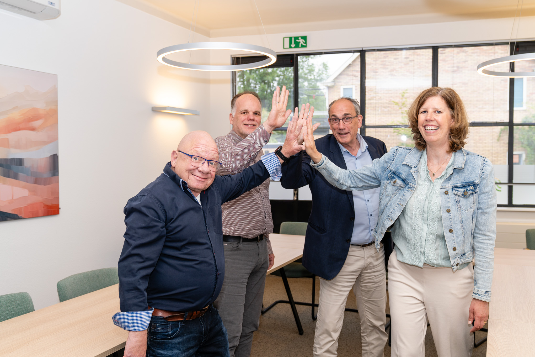 Medewerkers en managers geven elkaar een high five tijdens overleg over nieuwe software en verandering.